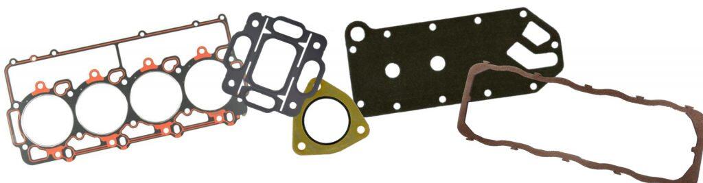 A collection of various engine gaskets, including head gaskets, manifold gaskets, and seals, laid out against a white background, suggesting a complete overhaul or repair kit.